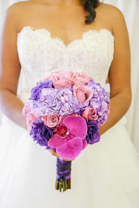 Bride holds a vibrant purple pink wedding flower bouquet