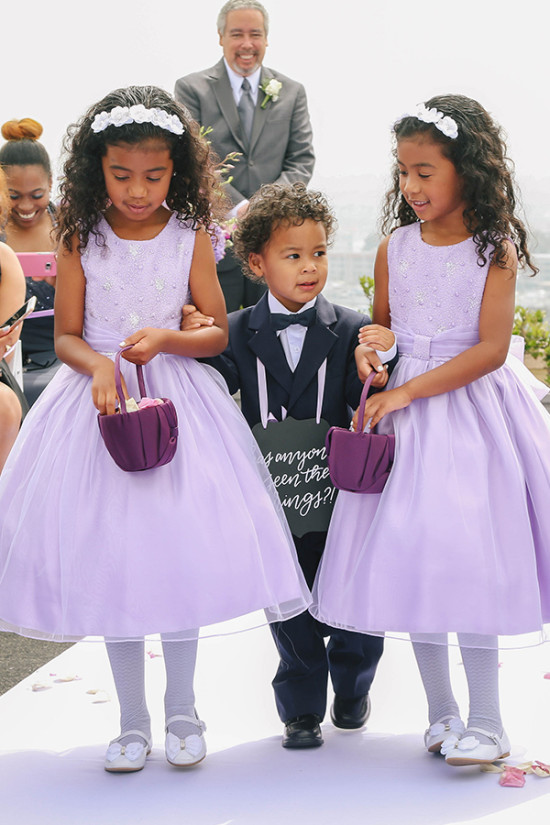 Adorable flower girls in lavender dresses walk down the aisle