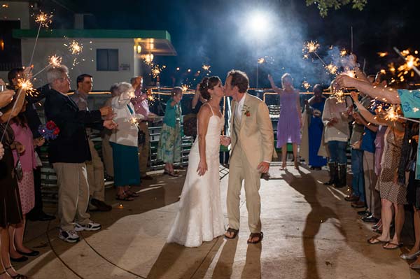 Bride and groom kiss surrounded by sparklers at wedding