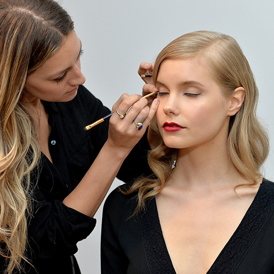 Makeup artist applying eyeliner to model's eye