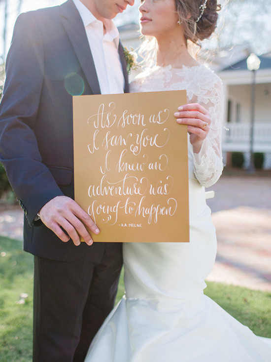 Newlyweds holding a love quote sign at their wedding