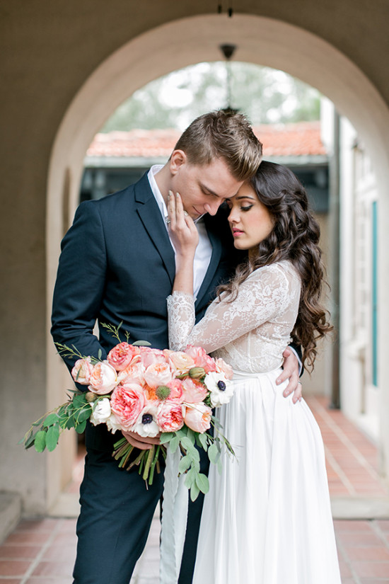 Elegant bride and groom embrace with a floral bouquet