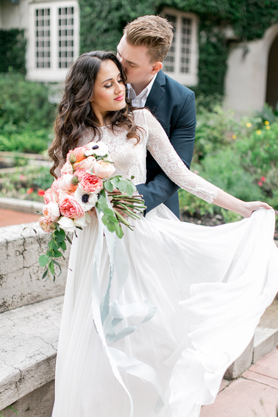 Bride with bouquet kisses by groom on wedding day