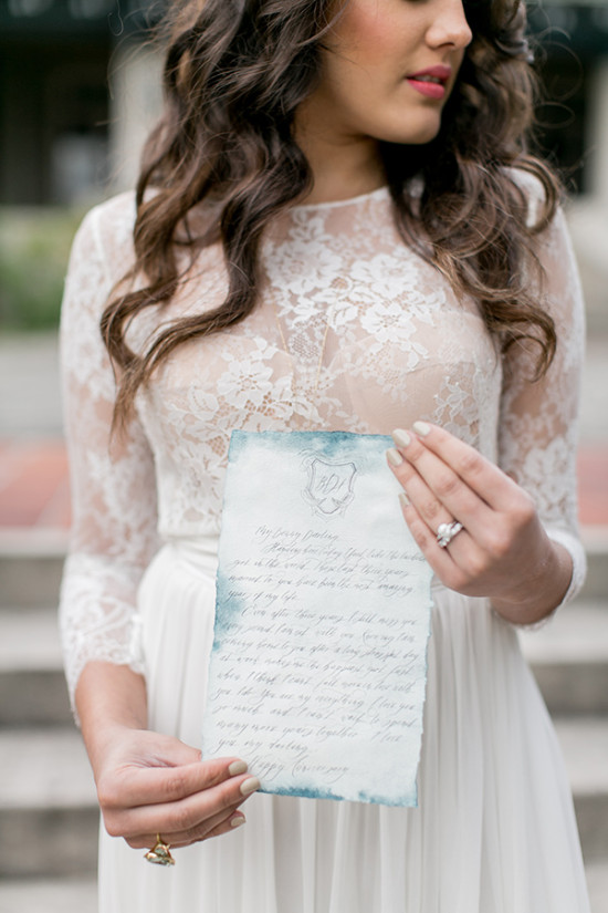 Bride in lace dress holds handwritten love letter