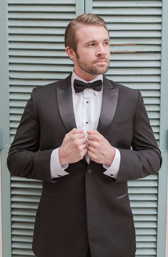 Man in black tuxedo with bow tie posing indoors