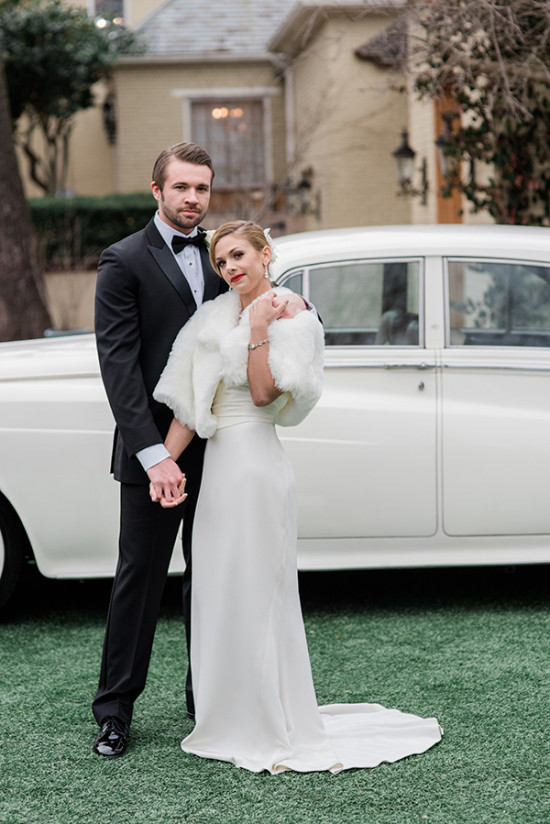 Elegant wedding couple poses with classic car