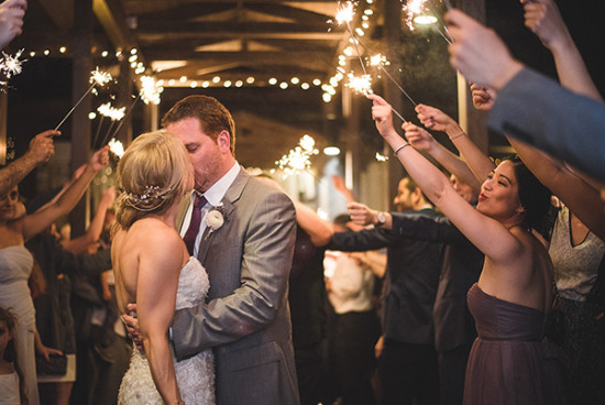 Bride and groom kiss surrounded by sparklers at wedding