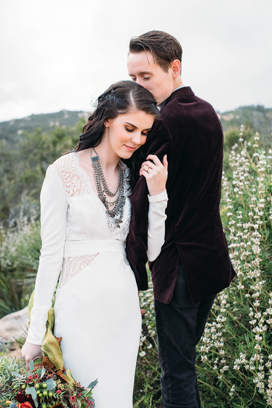Affectionate groom kisses bride head outdoor wedding