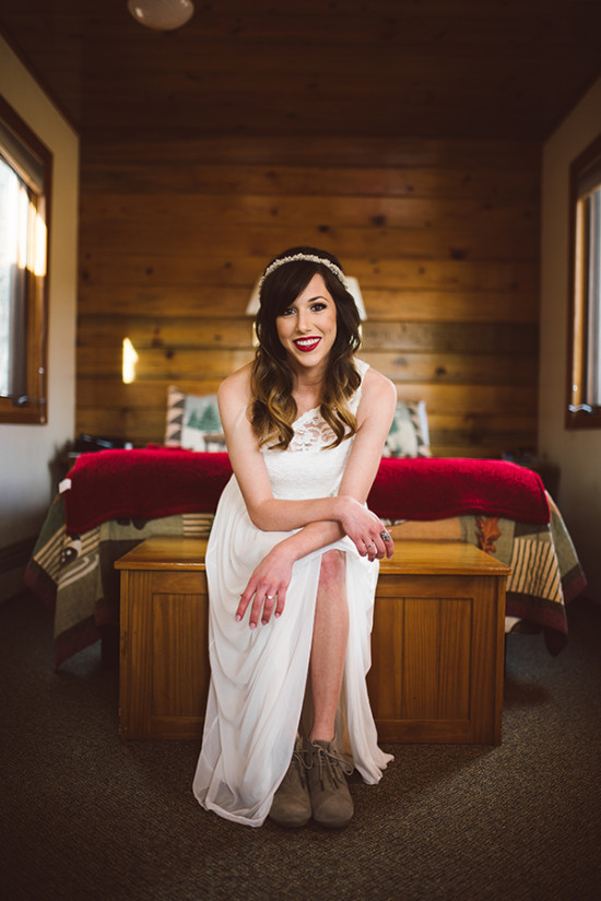 Bride in white dress and boots smiles in cabin room