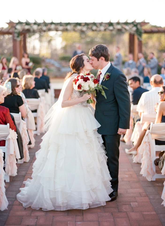 Newlyweds share a kiss during their outdoor wedding ceremony
