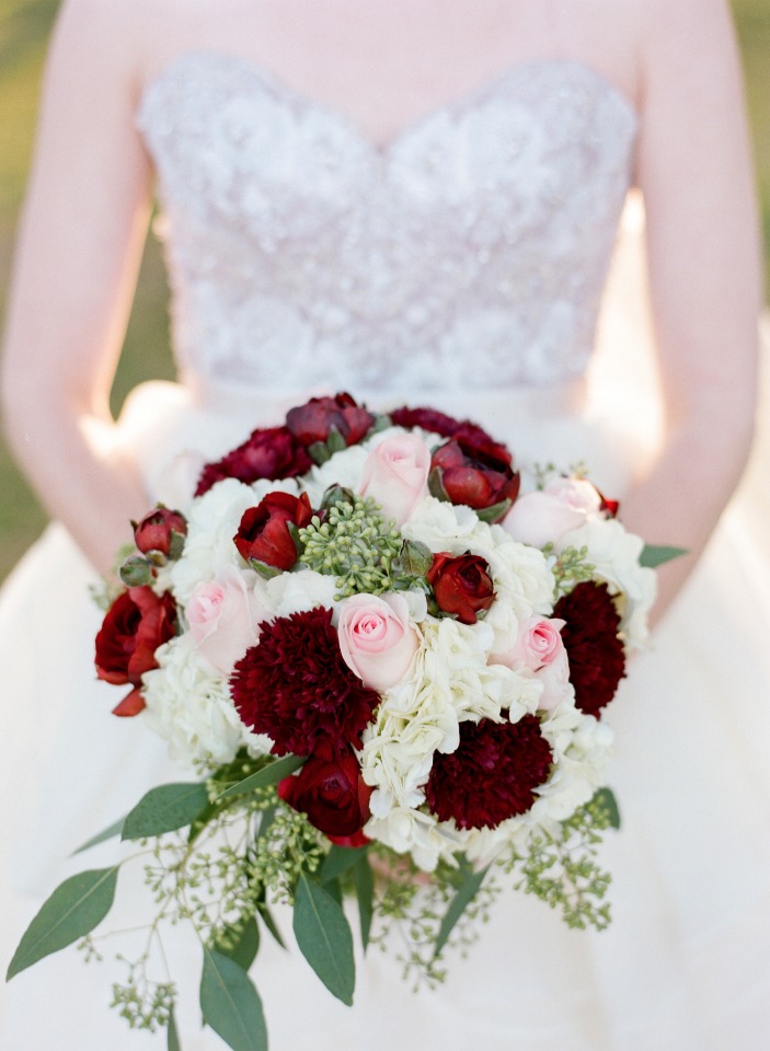 Bride holding a bouquet of burgundy and white flowers