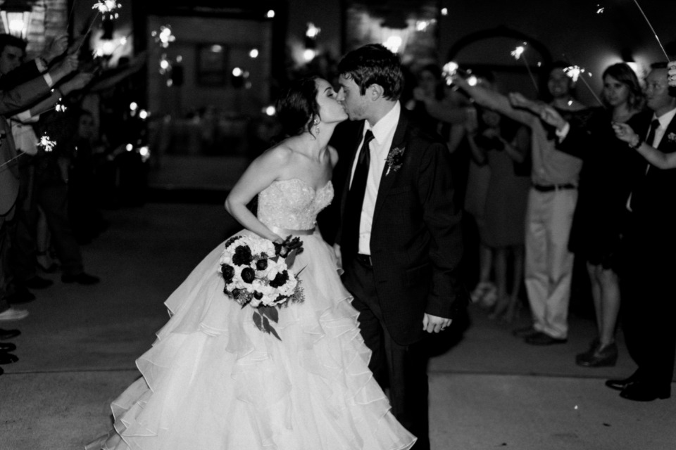 Black and white wedding kiss amid sparkler sendoff