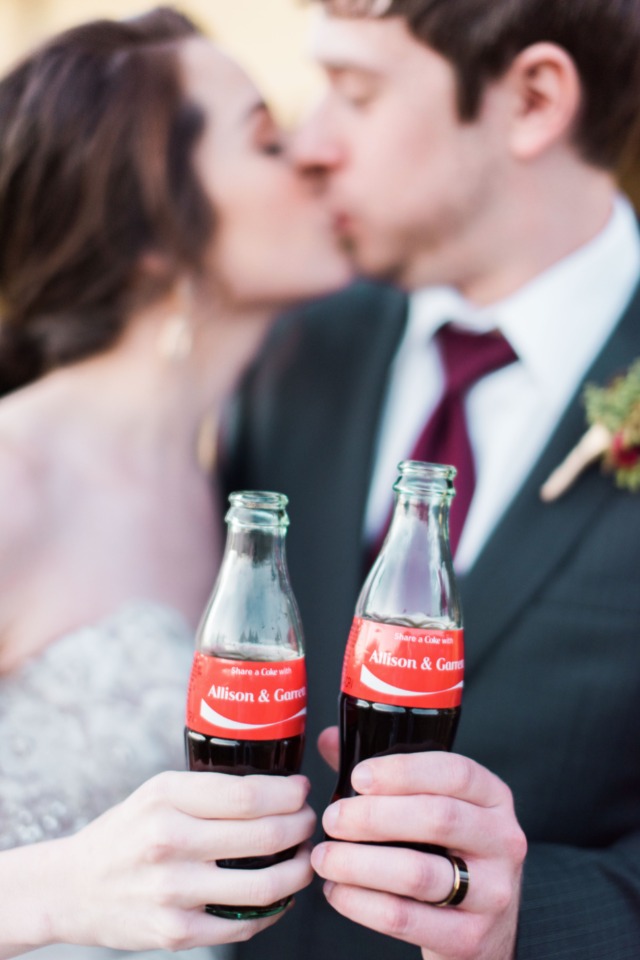 Bride and groom kissing with personalized Coke bottles