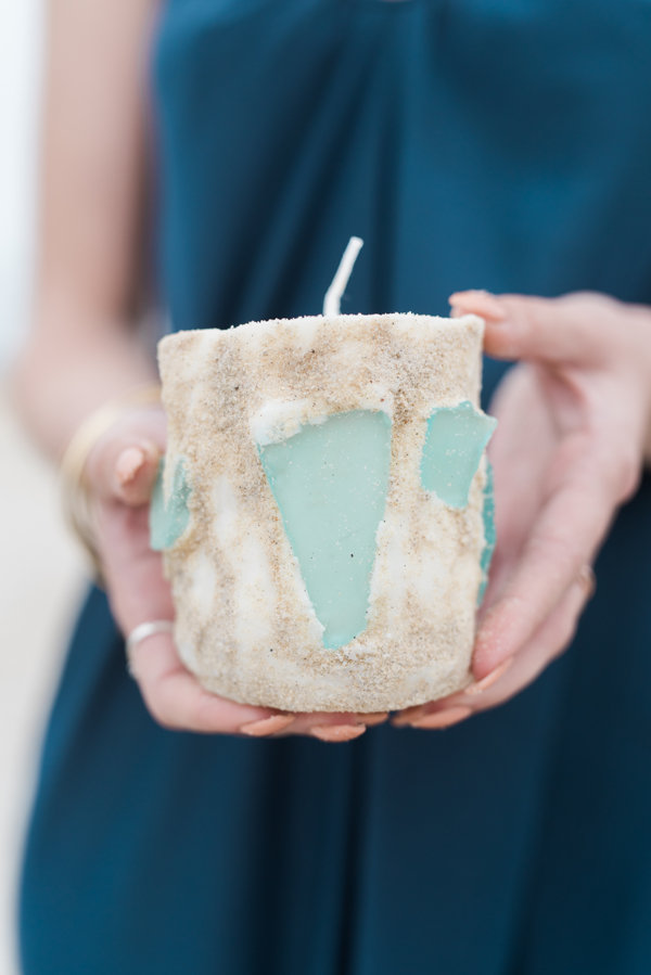 Hands holding a beach themed candle with sea glass