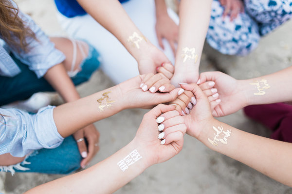 Friends hands together with gold tattoos at a bachelorette party