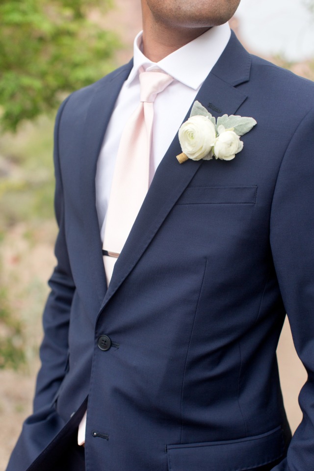 groom in navy suit with blush tie and white boutonniere 