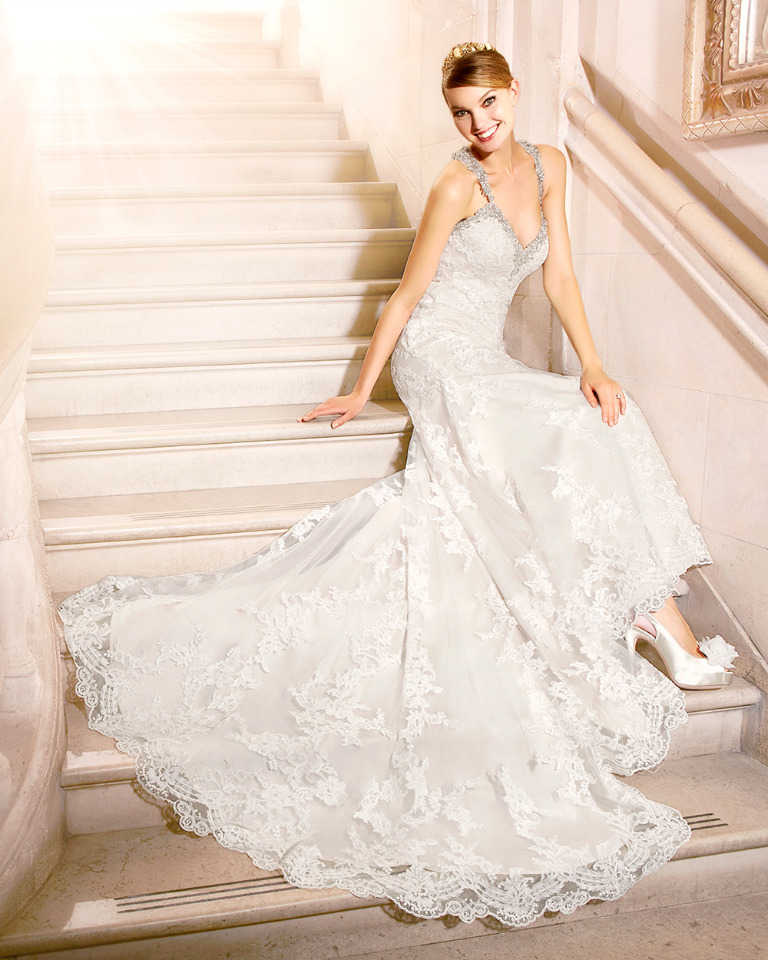 Bride poses on stairs in elegant lace wedding gown