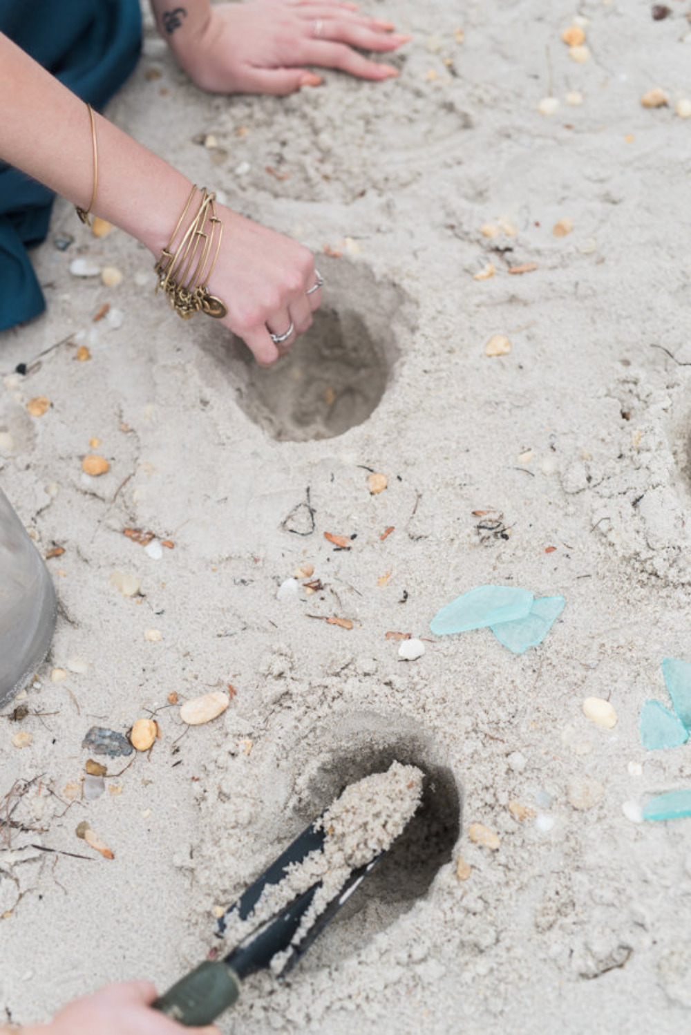 Beach fun digging holes in sand with shovel and sea glass