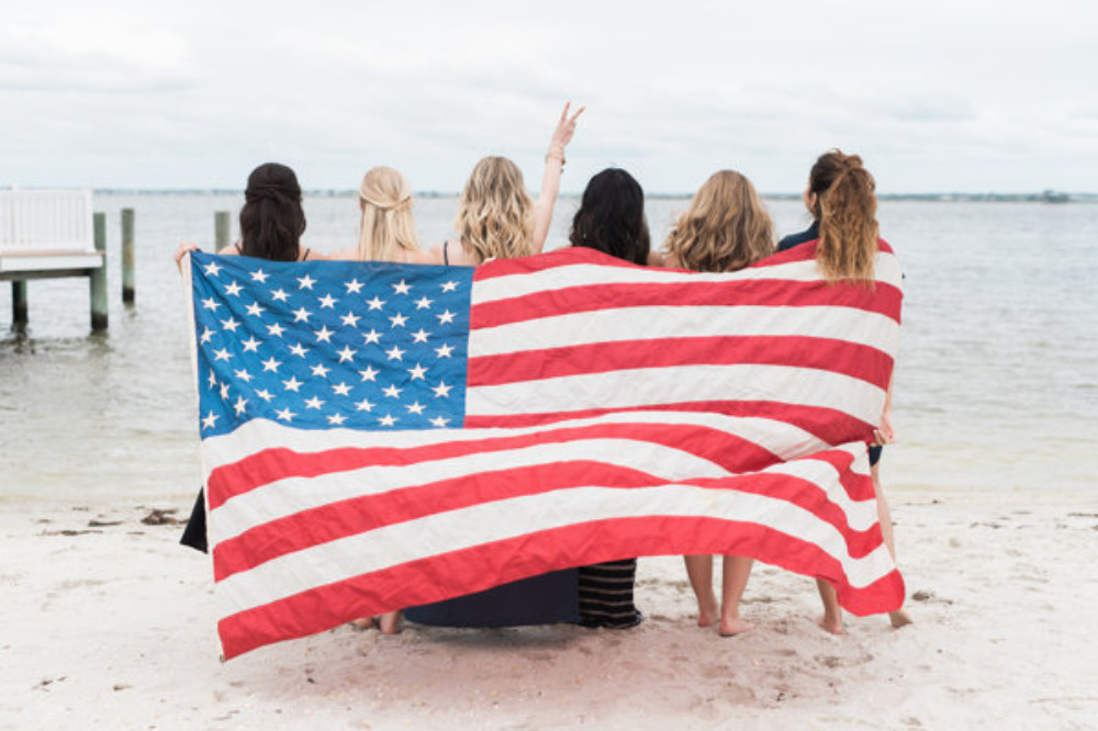 Girls holding American flag at beach patriotic scene