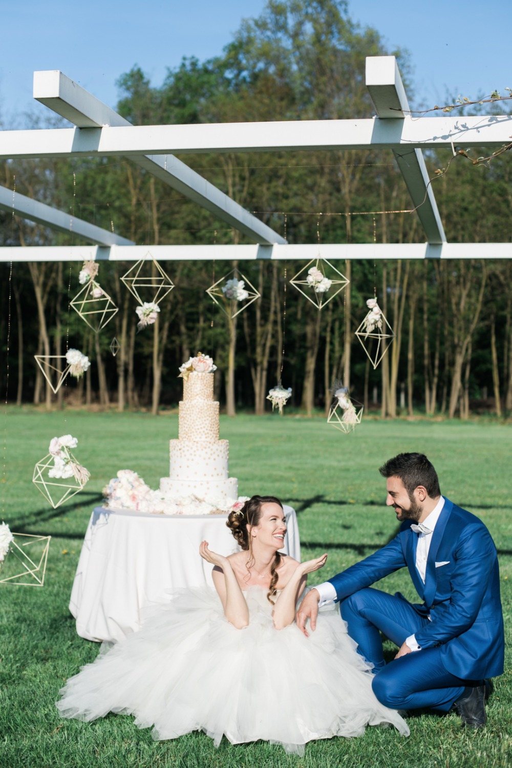 outdoor wedding cake display with hanging geometric backdrop