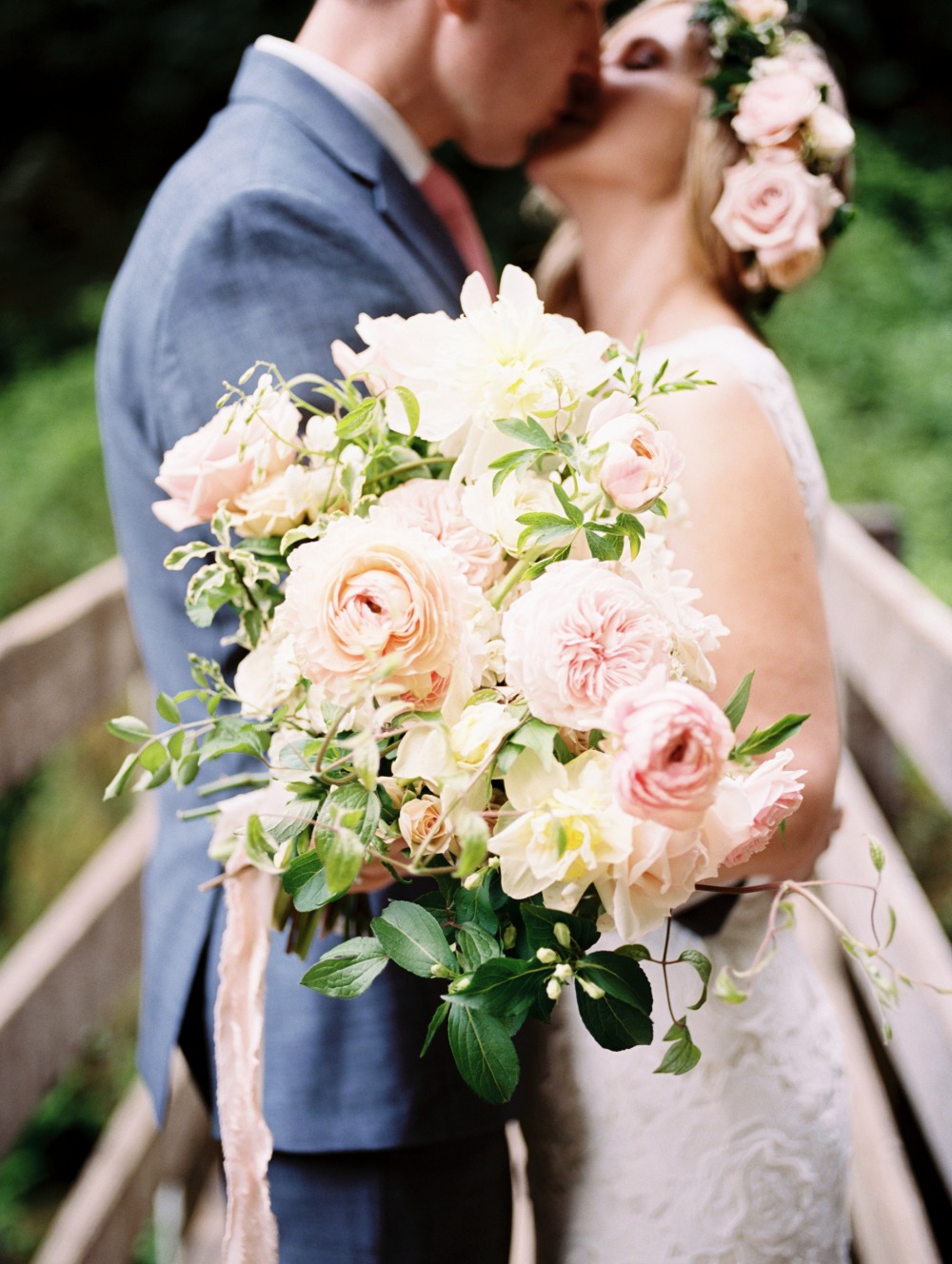 Bride and groom kissing with a lush floral bouquet