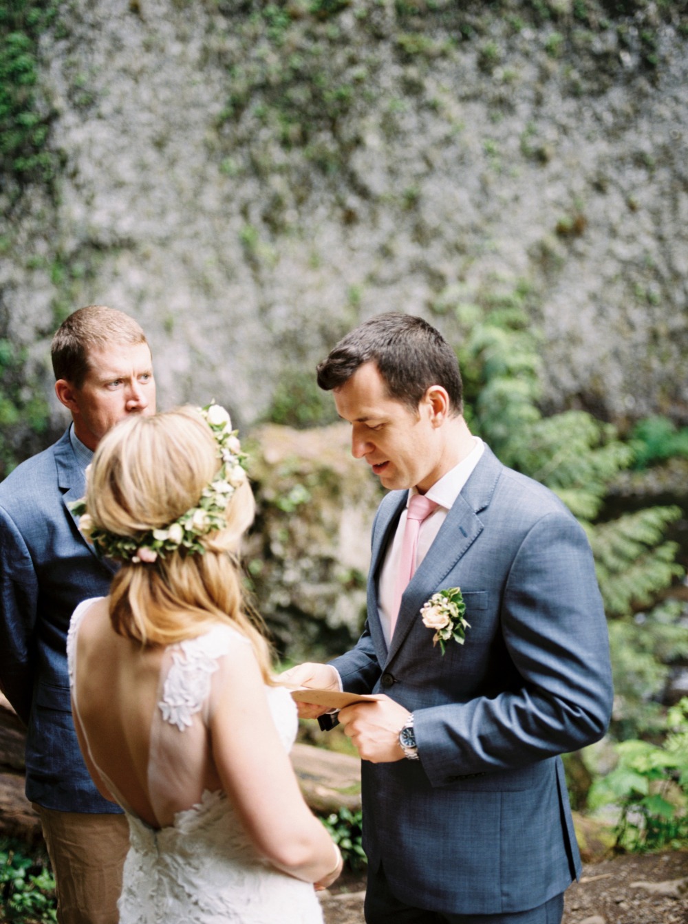 Groom reading vows to bride at outdoor ceremony