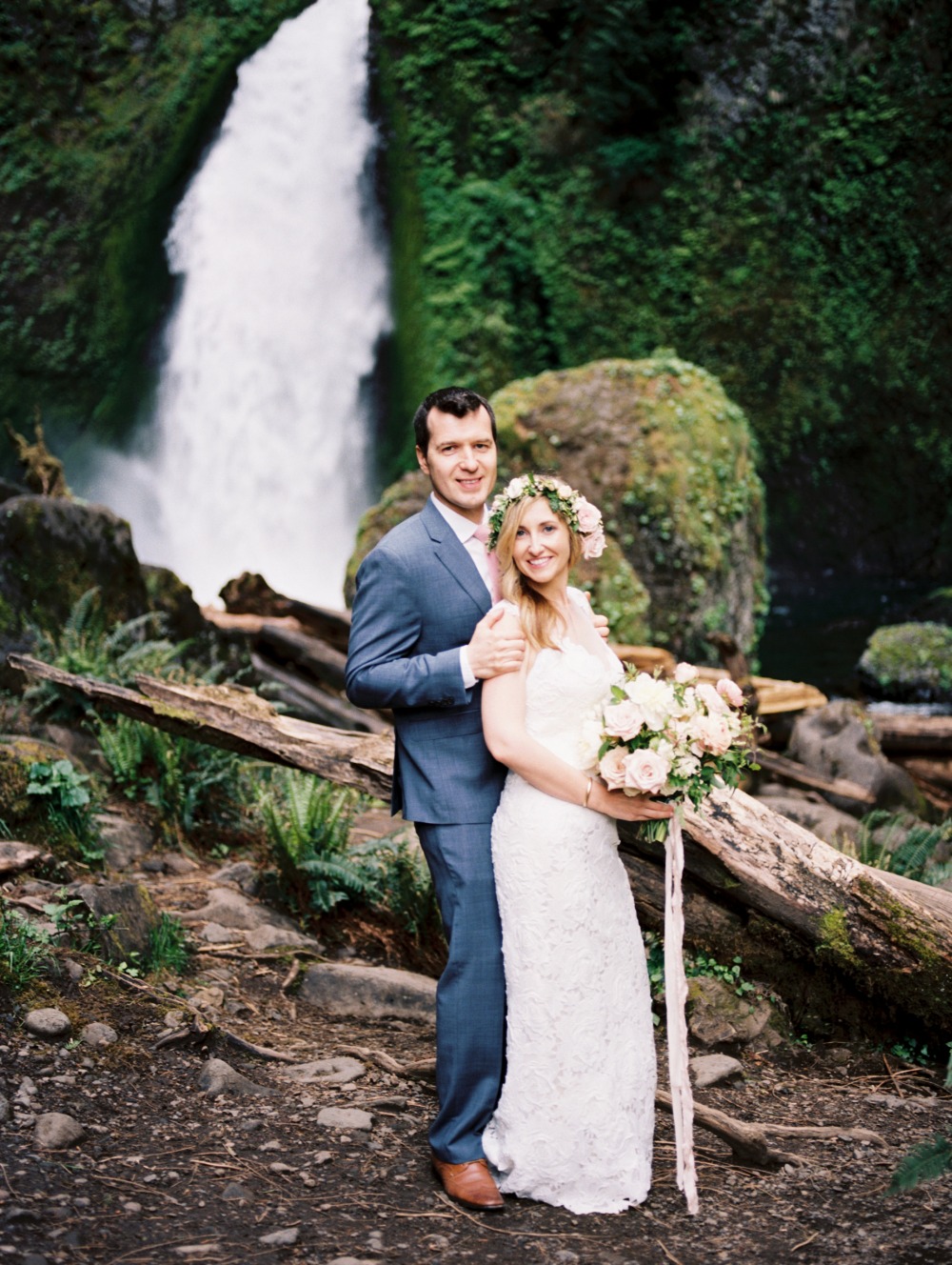 Happy couple posing by a waterfall on their wedding day