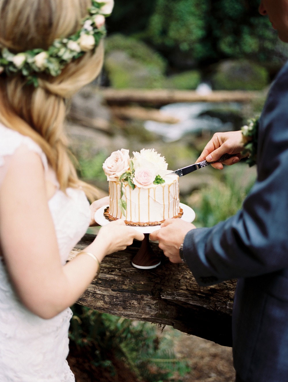 Bride and groom cut wedding cake in forest scenery
