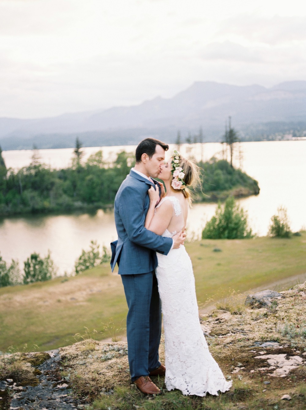 Bride and groom kissing overlooking lake