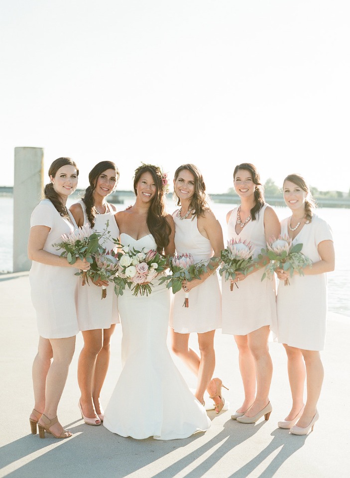 bridesmaids in varied styles of knee length white dresses