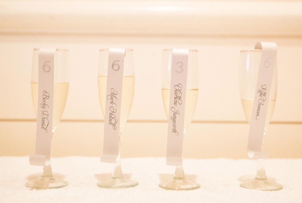 reception escort cards hanging off of a glass of champagne