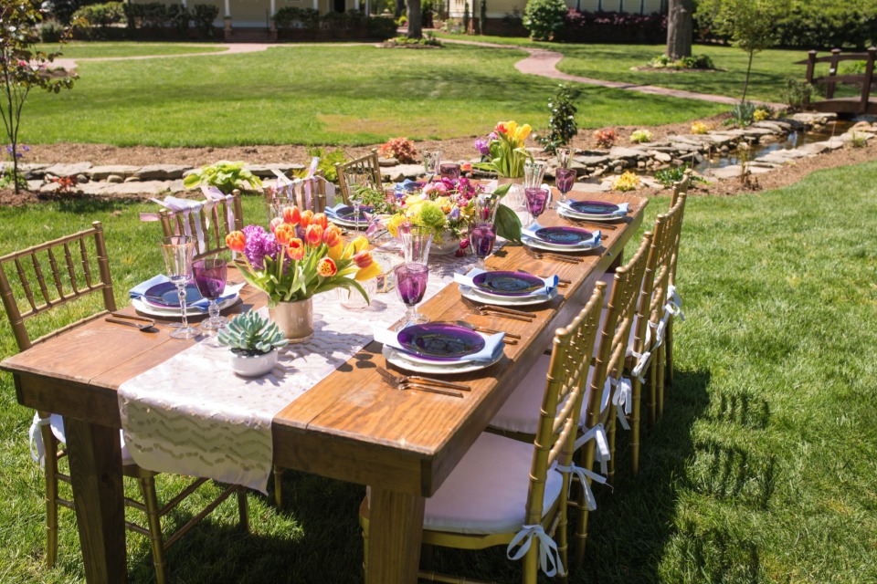 farm table with bright floral centerpieces and vintage china