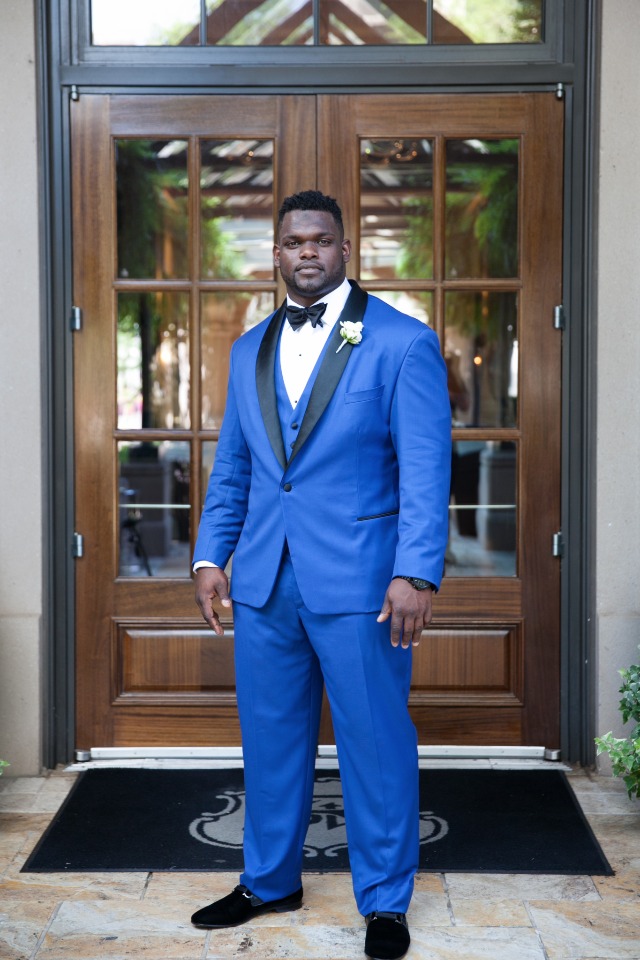 Man in stylish blue suit and bow tie stands posing