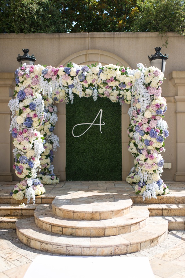 Floral wedding arch with initial on green backdrop