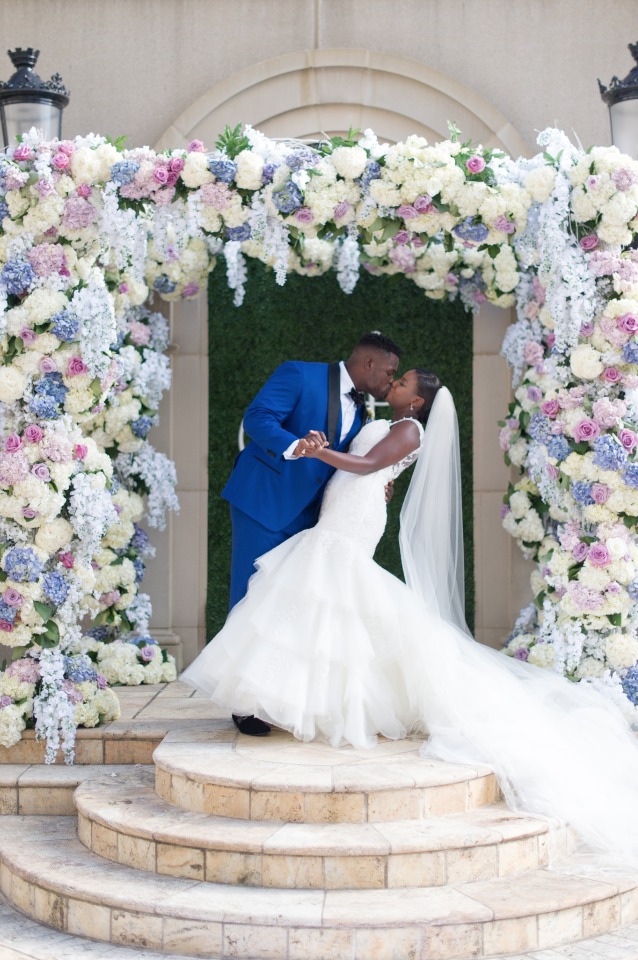 Bride and groom kissing under a floral wedding arch