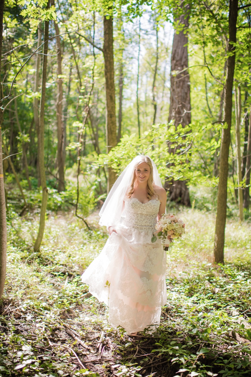 Bride in wedding dress in the woods holding flowers
