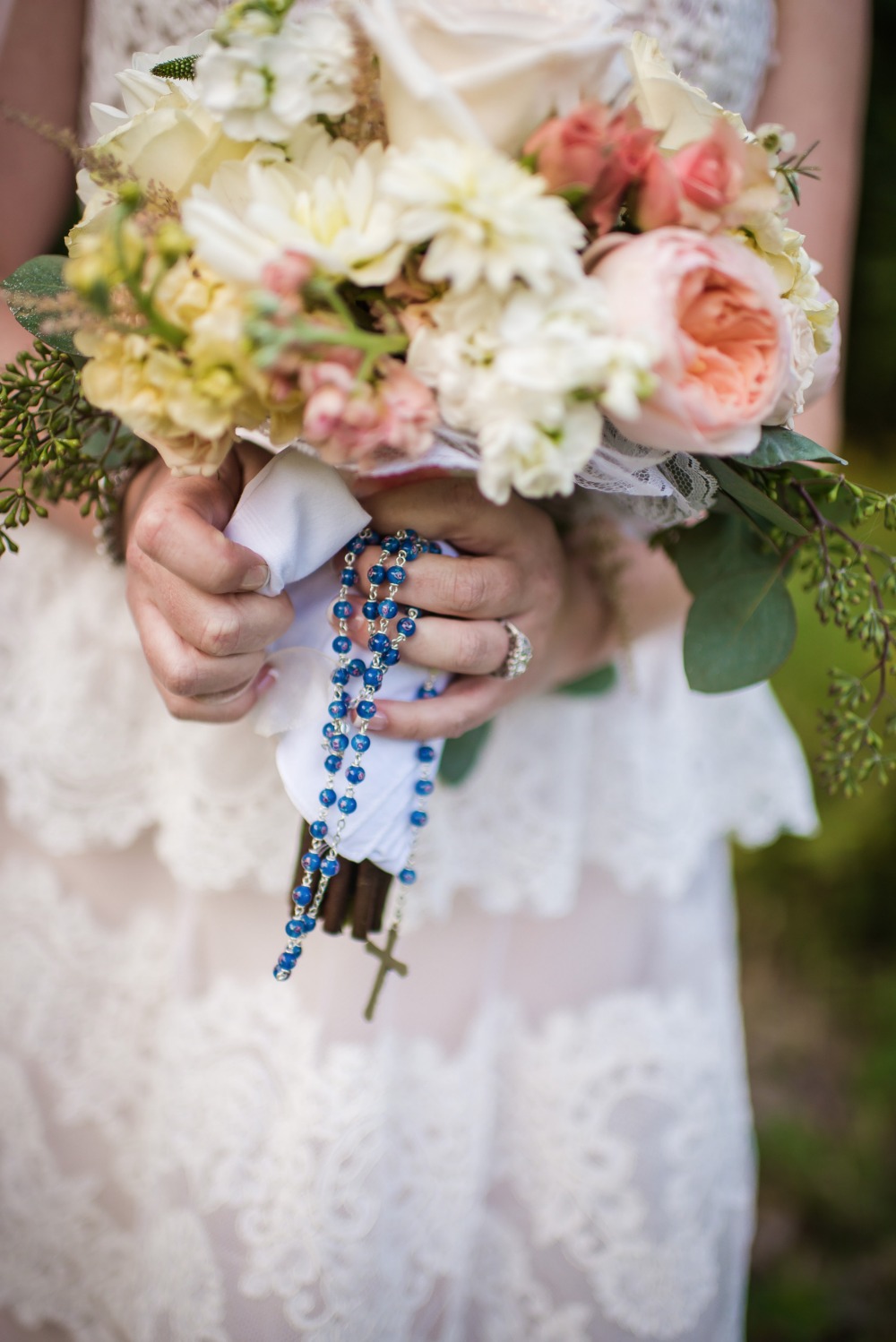 Bride holding wedding bouquet and blue rosary beads