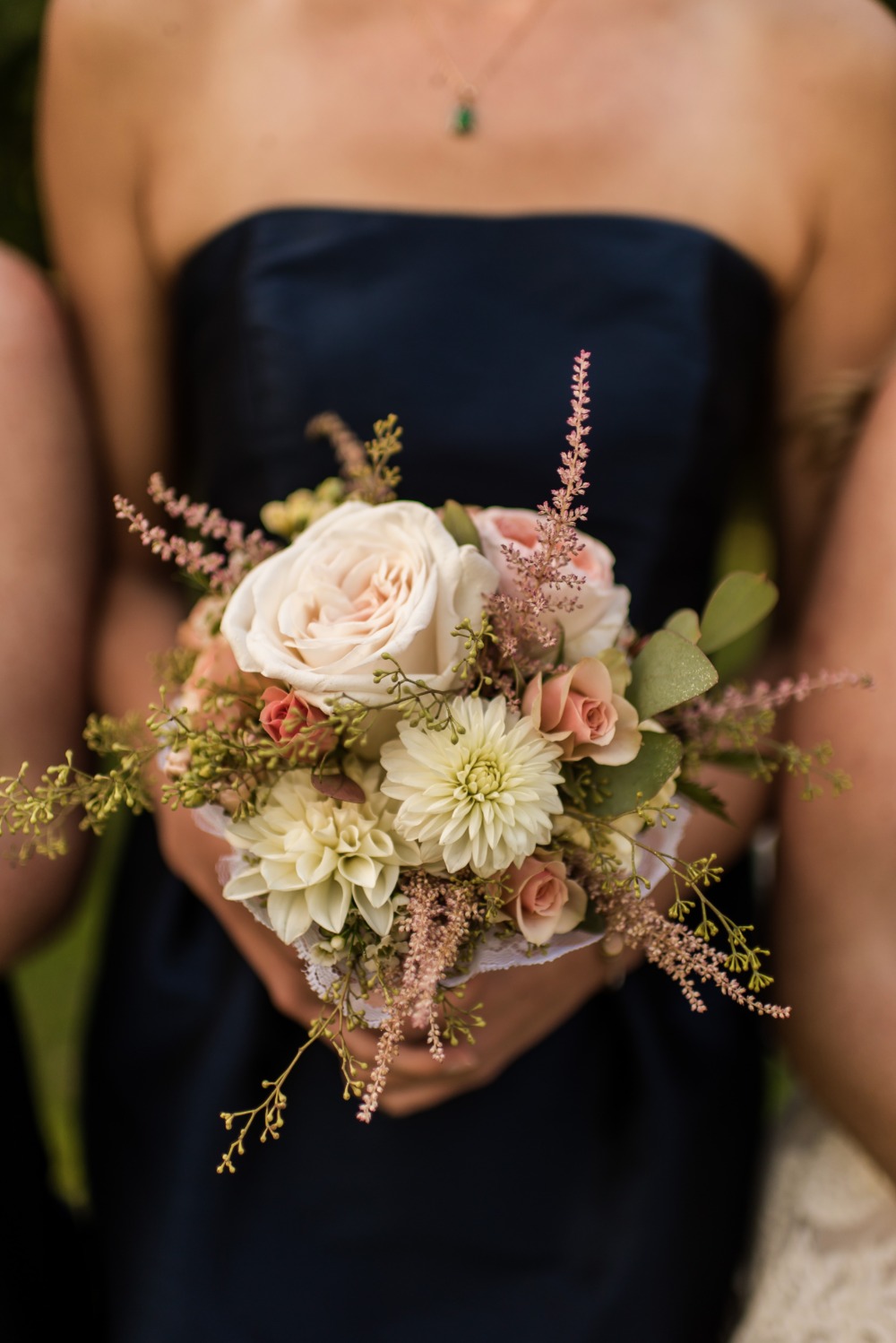 Bridesmaid holds pretty wedding bouquet of roses dahlias