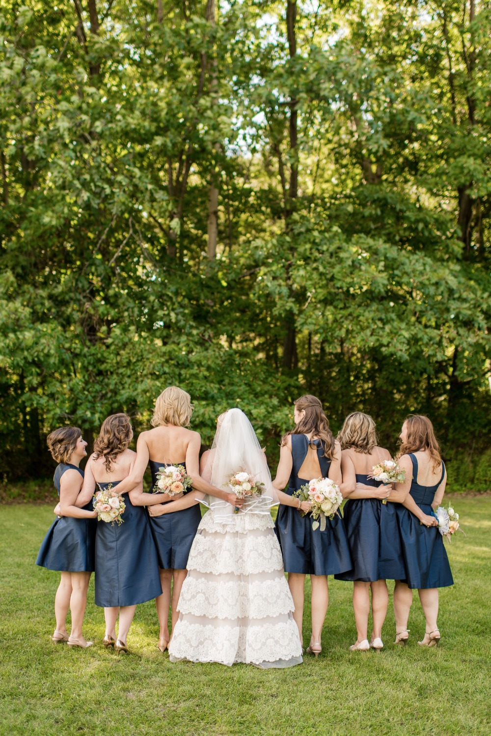 Bride and bridesmaids pose in navy dresses outdoors