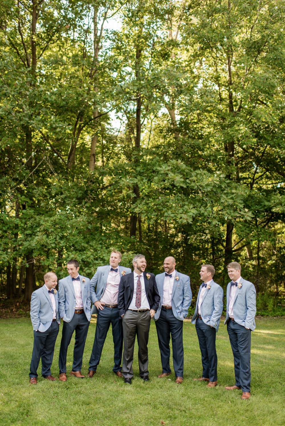 Groom and groomsmen laughing outdoors on wedding day