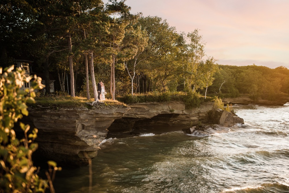 Romantic wedding couple on scenic lake cliff at sunset