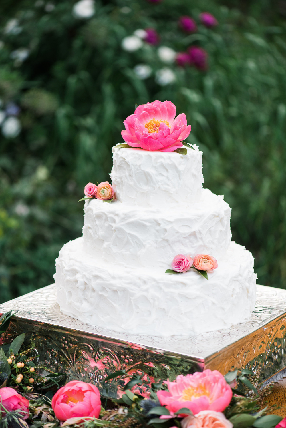 rustic white wedding cake with pink flower topper