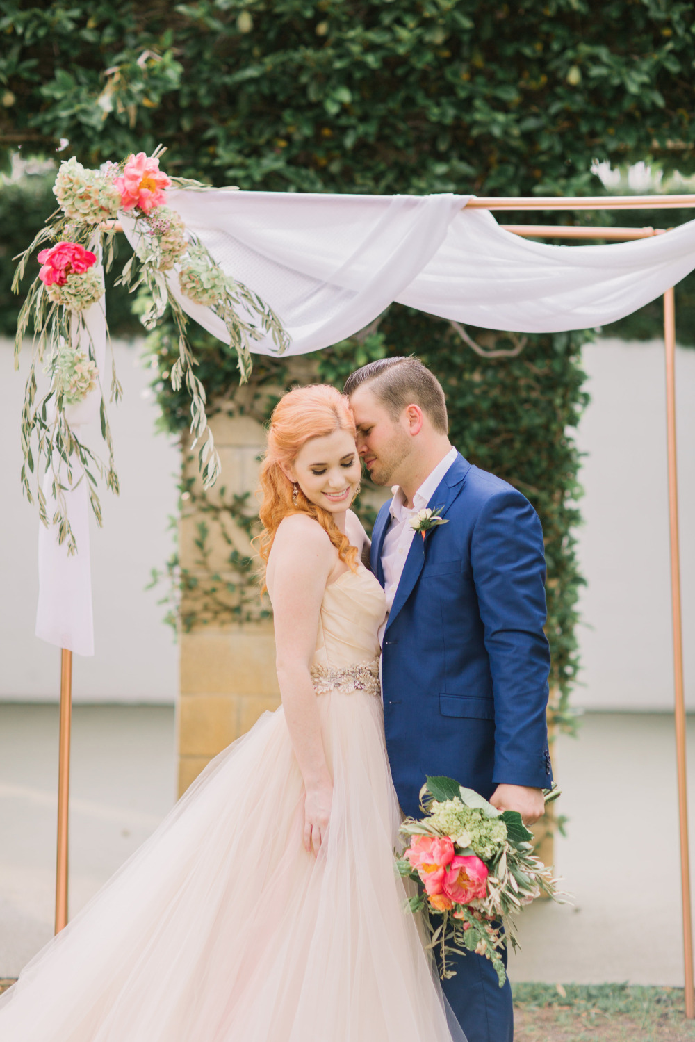 Romantic couple embracing under floral wedding arch