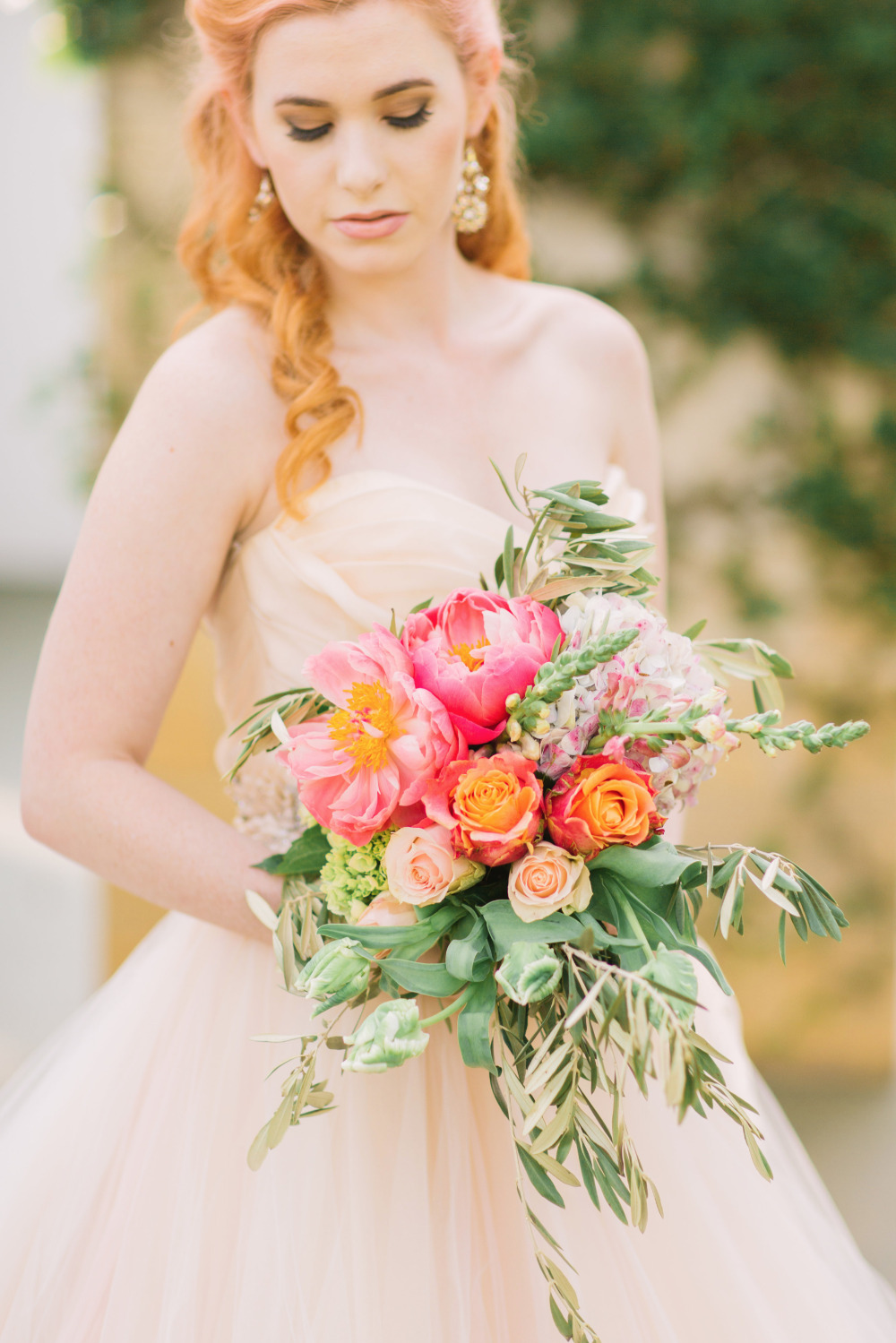 Bride in tulle dress holds colorful wedding bouquet