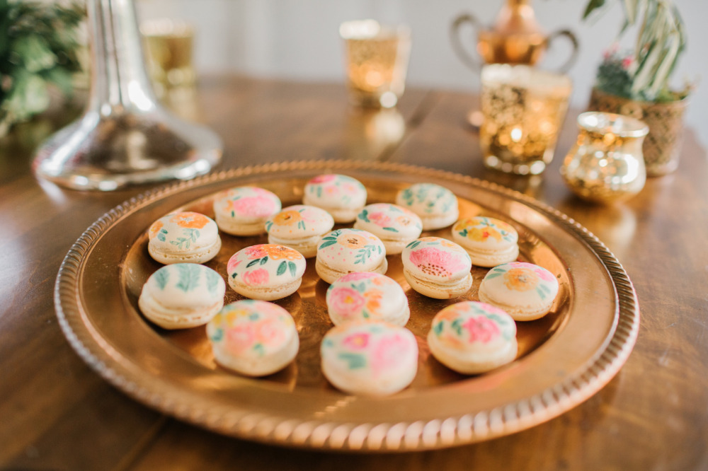 Floral painted macarons on a gold serving tray