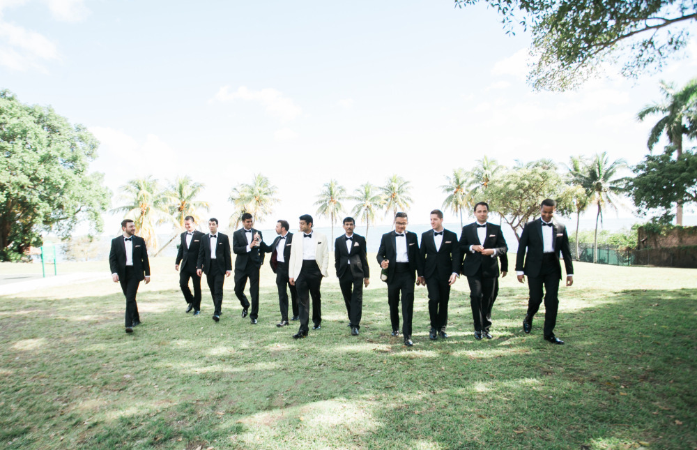 Groomsmen in tuxedos walking outdoors to wedding party