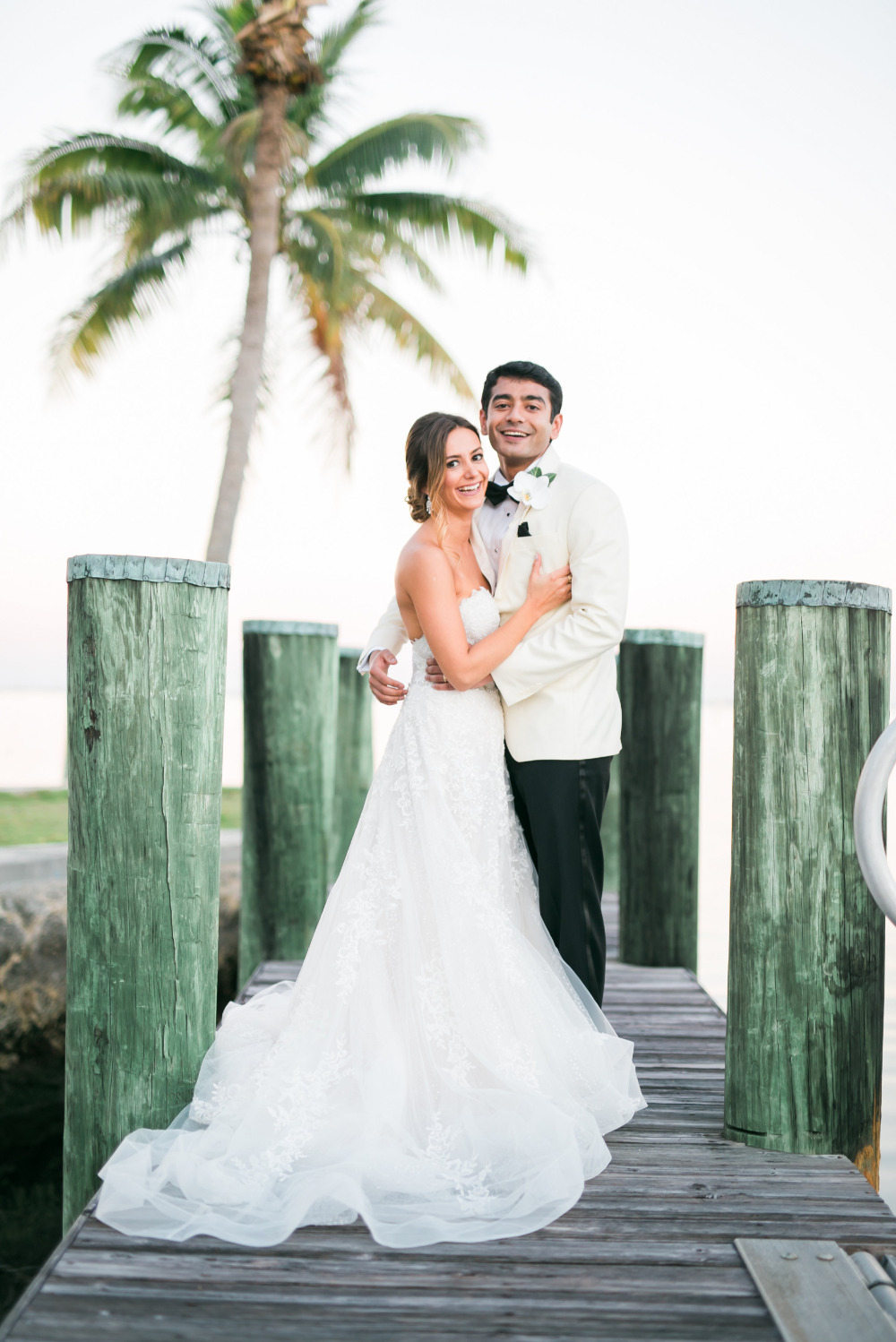 Bride and groom embrace on a tropical pier wedding day