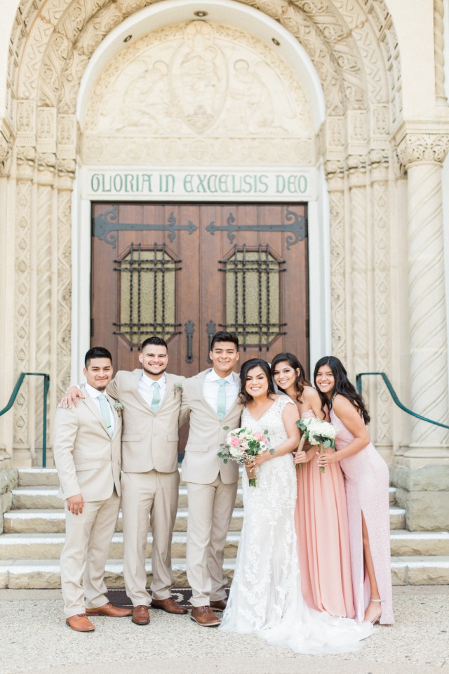 bridesmaids in long pink dresses and groomsmen in neutral and sage