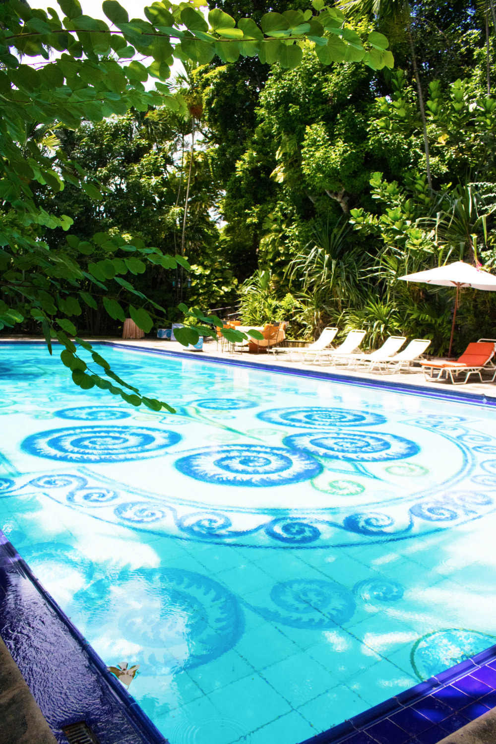 Tranquil blue pool with ornate design, surrounded by lush greenery