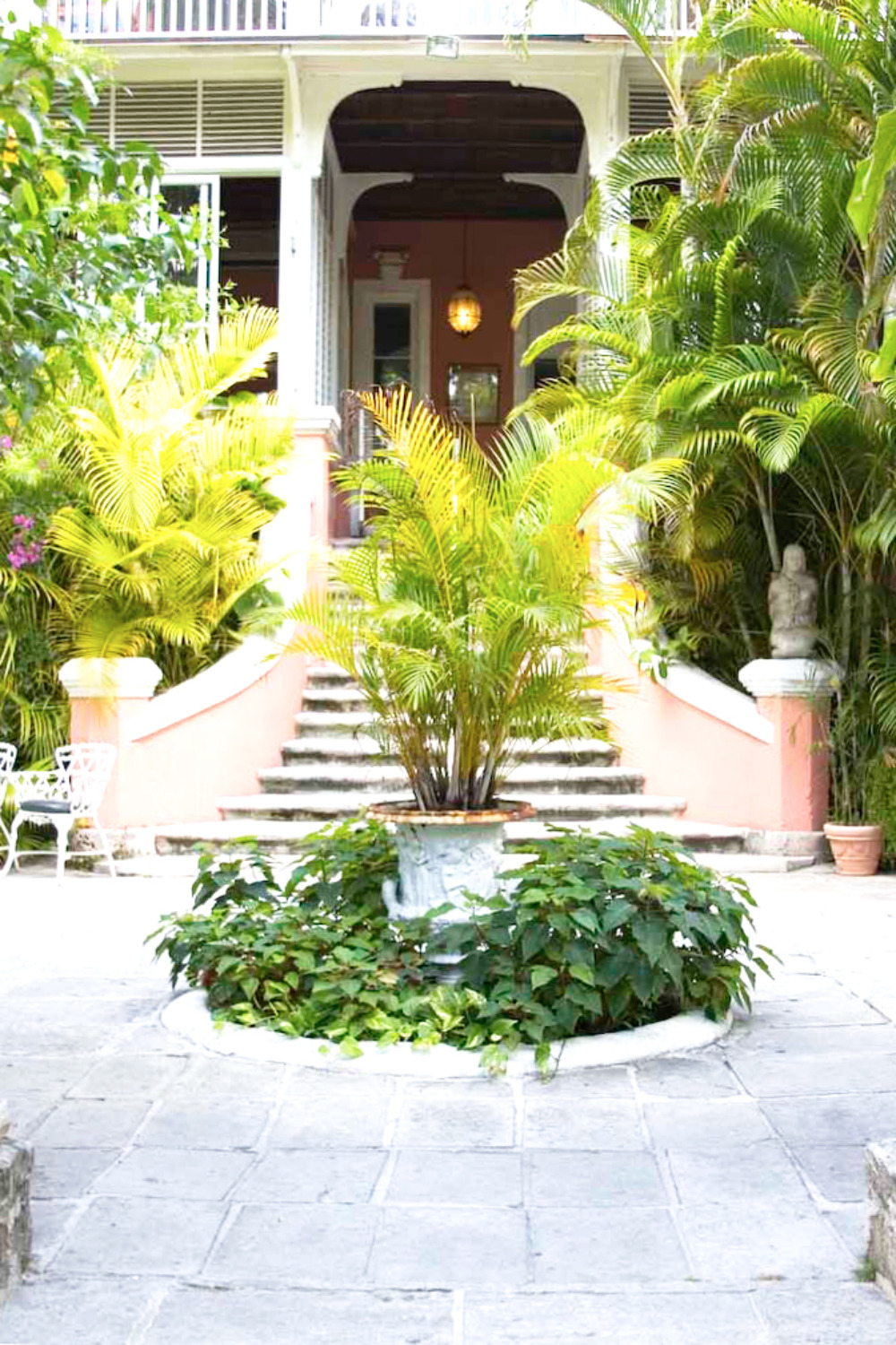 Lush tropical courtyard with pink staircase and fountain